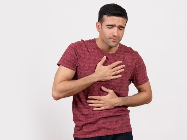 Man clutching chest in need of emergency heart care in Houston, TX